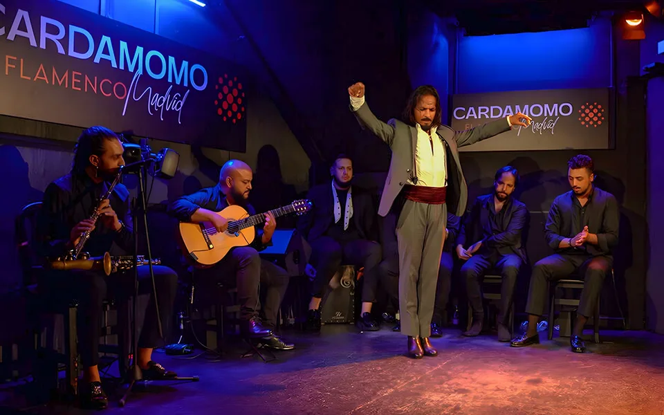 Eine Flamenco‑Tänzerin und sitzende Musiker bei Cardamomo