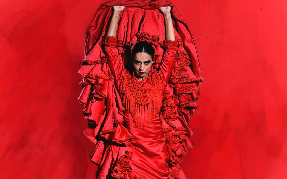 A flamenco dancer lifting a red ruffled dress