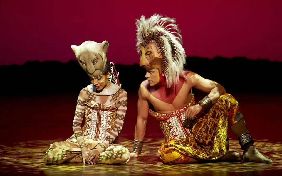 Two El Rey León performers wearing animal-inspired costumes