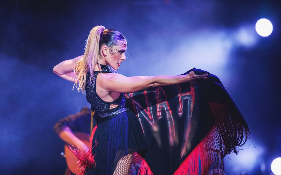 A WAH dancer holding a dark fringed shawl